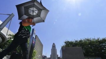 A pedestrian uses an umbrella while walking past City Hall in Los Angeles amid an ongoing heatwave on August 29, 2017, generating triple-digit temperatures in some southern California communities. Temperatures hit the mid 90F (34C). / AFP PHOTO / FREDERIC J. BROWN (Photo credit should read FREDERIC J. BROWN/AFP via Getty Images)