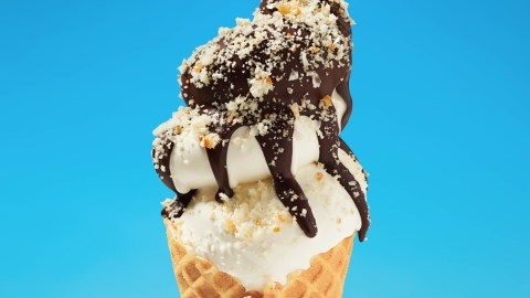 Helado de la marca Krispy Kreme en un cono y cubierto de chocolate y moronas de almendra.