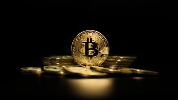 Representaciones de monedas de Bitcoin iluminadas en un fondo negro.