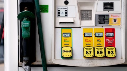 Una bomba de gasolina con la pistola de despacho colocada y diferentes tipos de combustible.