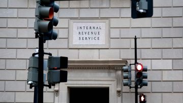 Facha del edificio del IRS con un letrero que indica el nombre de la oficina y unos semáforos.
