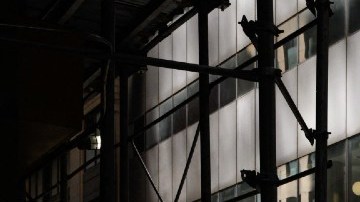 Personas que caminan en las sombras entre edificios.