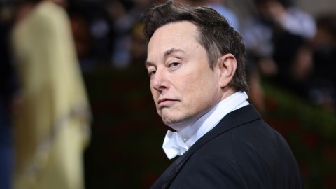 Elon Musk con un traje frac y mirando sobre su hombro