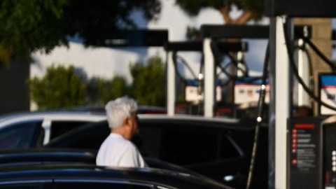 Imagen de varias personas esperando en la fila de una estación de servicio para cargar gasolina.