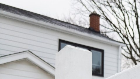 Un letrero de venta en color rojo en el patio de una vivienda.