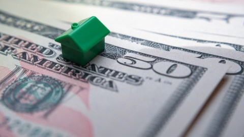 una pequeña casa de color verde sobre billetes de $50 dólares