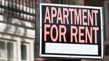 Un letrero de renta colocado frente a un edificio de apartamentos.