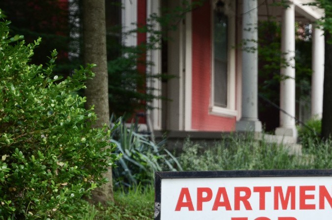 Un letrero de renta colocado en el jardín de una zona de apartamentos.
