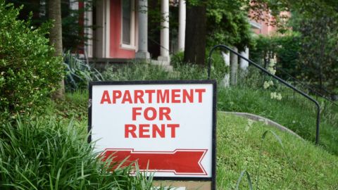 Un letrero de renta colocado en el jardín de una zona de apartamentos.
