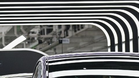 Un vehículo Model 3 de Tesla en un túnel, el dueño de la fábrica Elon Musk y gente con cámaras