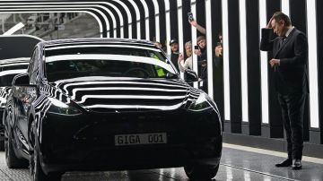 Un vehículo Model 3 de Tesla en un túnel, el dueño de la fábrica Elon Musk y gente con cámaras