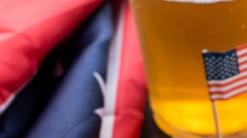 Dos hotdogs con banderas de los Estados Unidos , cerveza y papas fritas.