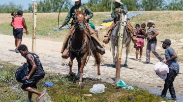 Agentes de la Patrulla Fronteriza a caballo intentan impedir que migrantes haitianos ingresen a un campamento a orillas del Río Grande en 2021.