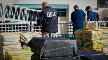 A DEA officer stands next to packages of marijuana and cocaine during an offload at Port Everglades, in Fort Lauderdale, Florida on November 22, 2021. - The US Coast Guard offloaded millions of dollars of drugs which were intercepted at sea at Port Everglades on Monday morning. (Photo by Eva Marie UZCATEGUI / AFP) (Photo by EVA MARIE UZCATEGUI/AFP via Getty Images)