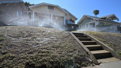 TOPSHOT - Despite water conservation regulations forbiding daytime watering, irrigation sprinklers jet water over a front lawn of degraded soil, July 12, 2022 during California's historic drought. - Authorities are encouraging residents to replace their lawns with waterwise gardens that requires very little irrigation by using native and non-native drought tolerant plants coupled with terraforming that captures rainwater, to save water amidst California's historic drought. (Photo by Robyn Beck / AFP) (Photo by ROBYN BECK/AFP via Getty Images)