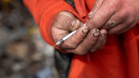 Un desamparado sostiene una jeringuilla después de inyectarse metanfetamina en el brazo.