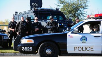Members of a SWAT Team watch from the roadside as police lead a convoy of of vehicles, including the hearse carrying the body of slain Riverside police officer Michael Crain on its approach to the Grove Community Church in Riverside, California, on February 13, 2013. Law enforcement personnel from across the state, and others close to the deceased gathered to pay their final respects to the policeman killed last week in what the city's police chief described as a "cowardly ambush.'' Crain was fatally shot last Thursday when he and his partner ran afoul of fugitive Christopher Jordan Dorner, the fired Los Angeles Police Department officer on a killing spree which ended last night in the mountains of nearby Big Bear, authorities report. AFP PHOTO / Frederic J. BROWN (Photo credit should read FREDERIC J. BROWN/AFP via Getty Images)