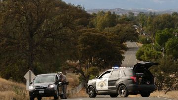 A Highway Patrol officer speaks to a woman while blocking off a road to traffic after a shooting on November 14, 2017, in Rancho Tehama, California - Four people were killed and nearly a dozen were wounded, including several children, when a gunman went on a rampage at multiple locations, including a school in rural northern California. (Photo by Elijah Nouvelage / AFP) (Photo by ELIJAH NOUVELAGE/AFP via Getty Images)