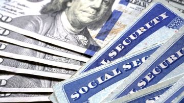 Billetes de $100 dólares se ven debajo de tarjetas de seguridad social de Estados Unidos.