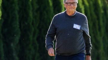 Imagen de Bill Gates vestido con un suéter de color gris mientras camina entre unos árboles.