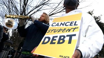 Un hombre sostiene un letrero de color amarillo en el que se exige la cancelación de las deudas estudiantiles.