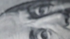 Dos billetes de $100 dólares sobre una tela de color café.