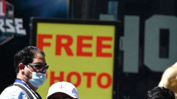 Varias personas que usan mascarilla contra la covid-19 esperan el paso en un cruce peatonal.