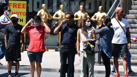 Varias personas que usan mascarilla contra la covid-19 esperan el paso en un cruce peatonal.