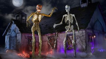 Dos esqueletos de plástico está de pie en un set arreglado de Halloween.