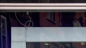 Un hombre camina frente a una tienda de la marca GAP, en la que hay letreros de rebajas.