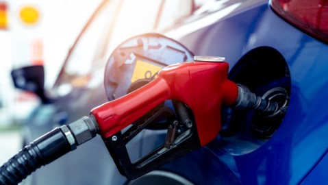 Un automóvil de color azul carga gasolina.