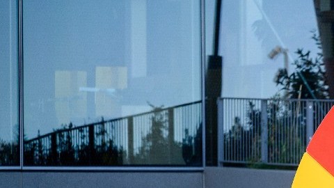 Un logotipo de Google se ve frente a un edificio de oficinas, mientras una persona camina con una caja en las manos.