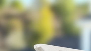 Un letrero de venta en madera frente a una vivienda en segundo plano fuera de foco.