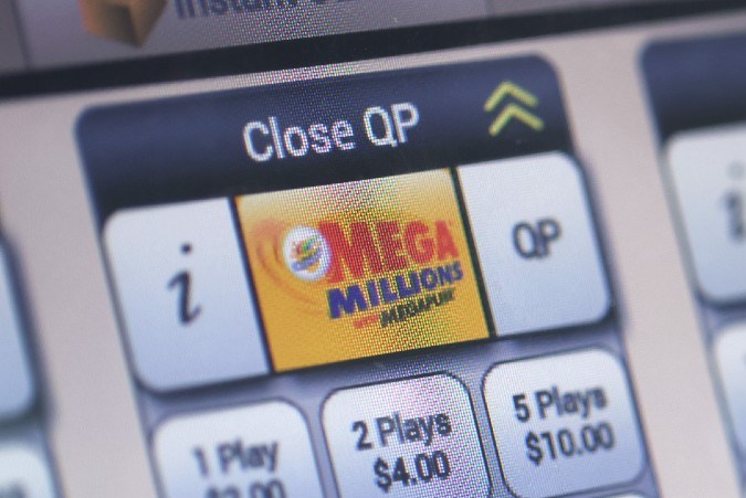 Imagen de una pantalla en la que se ve una mano que selecciona un juego de lotería.