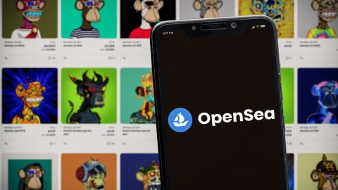 Imagen de la pantalla de un teléfono celular con el logotipo del mercado de NFT OpenSea con el fondo de varios NFT con la imagen de monos.
