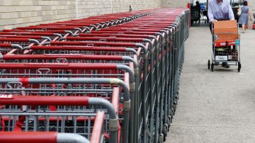 Una persona empuja un carrito de supermercado justo a un costado de una fila de varios otros carritos empotrados unos con otros.