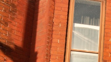 Imagen de un cartel de renta en color rojo frente a un departamento.