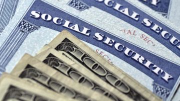 Billetes de $100 dólares sobre tarjetas de seguridad social de Estados Unidos.