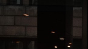 Una mujer camina frente a una sucursal de la cadena Starbucks, en la que se distingue su logotipo en color verde y blanco.