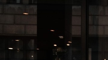 Una mujer camina frente a una sucursal de la cadena Starbucks, en la que se distingue su logotipo en color verde y blanco.