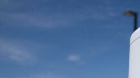 Una estación de carga eléctrica de la marca Tesla con un vehículo de la misma marca en el fondo.