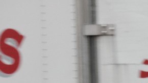 Imagen de dos trabajadores que cargan cosas, entre camiones.