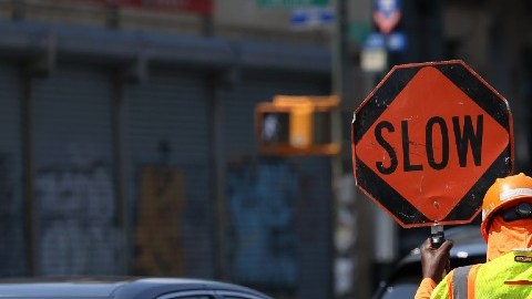 Un trabajador sostiene una señal de tránsito en medio del cierre de una calle por obras.