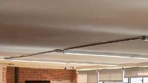 Un oficina con estaciones de trabajo y computadoras vacías, con una persona que ocupa un sitio de trabajo.