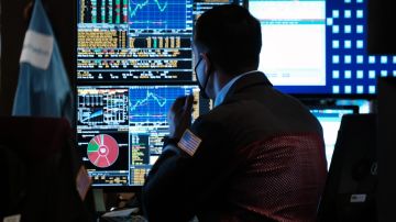 Una persona observa monitores con indicadores financieros y bursátiles en Wall Street.