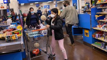 Una niña coloca productos en un carrito de supermercado dentro de una tienda de Walmart.