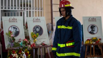 Un bombero camina junto a las fotos y los ataúdes de los fallecidos en los incendios de Matanzas.