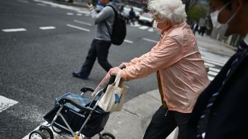 An elderly woman wearing a face mask crosses a street in Tokyo's Tsukiji area on March 27, 2020. (Photo by CHARLY TRIBALLEAU / AFP) (Photo by CHARLY TRIBALLEAU/AFP via Getty Images)