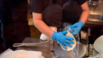 A worker at The Original Ninfa's wears gloves while making tortillas for takeout orders amid the novel coronavirus pandemic on May 1, 2020 in Houston, Texas. - Texas on Friday became the largest US state to begin easing coronavirus lockdown measures despite reporting a single-day high in deaths. Stores, restaurants, movie theaters, malls, museums and libraries were allowed to reopen in the Lone Star State but with limited occupancy -- just 25 percent of their capacity. (Photo by Mark Felix / AFP) (Photo by MARK FELIX/AFP /AFP via Getty Images)