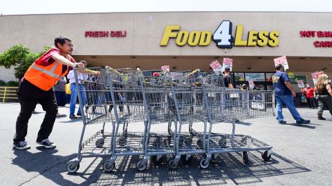 A grocery store worker pushes shopping carts as fellow workers, represented by the United Food and Commercial Workers International Union (UFCW), hold a boycott rally in front of a Food4Less Supermarket in Los Angeles, California on May 12, 2021, protesting alleged lack of progress on contract negotiations which began in January. - US job openings reached a record 8.1 million in March but businesses are struggling to find enough workers. (Photo by Frederic J. BROWN / AFP) (Photo by FREDERIC J. BROWN/AFP via Getty Images)